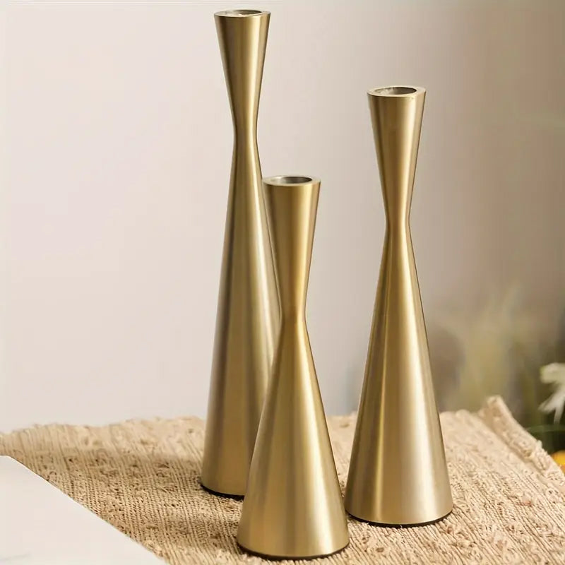 Three gold vases of different heights on a textured surface with a blurred background
