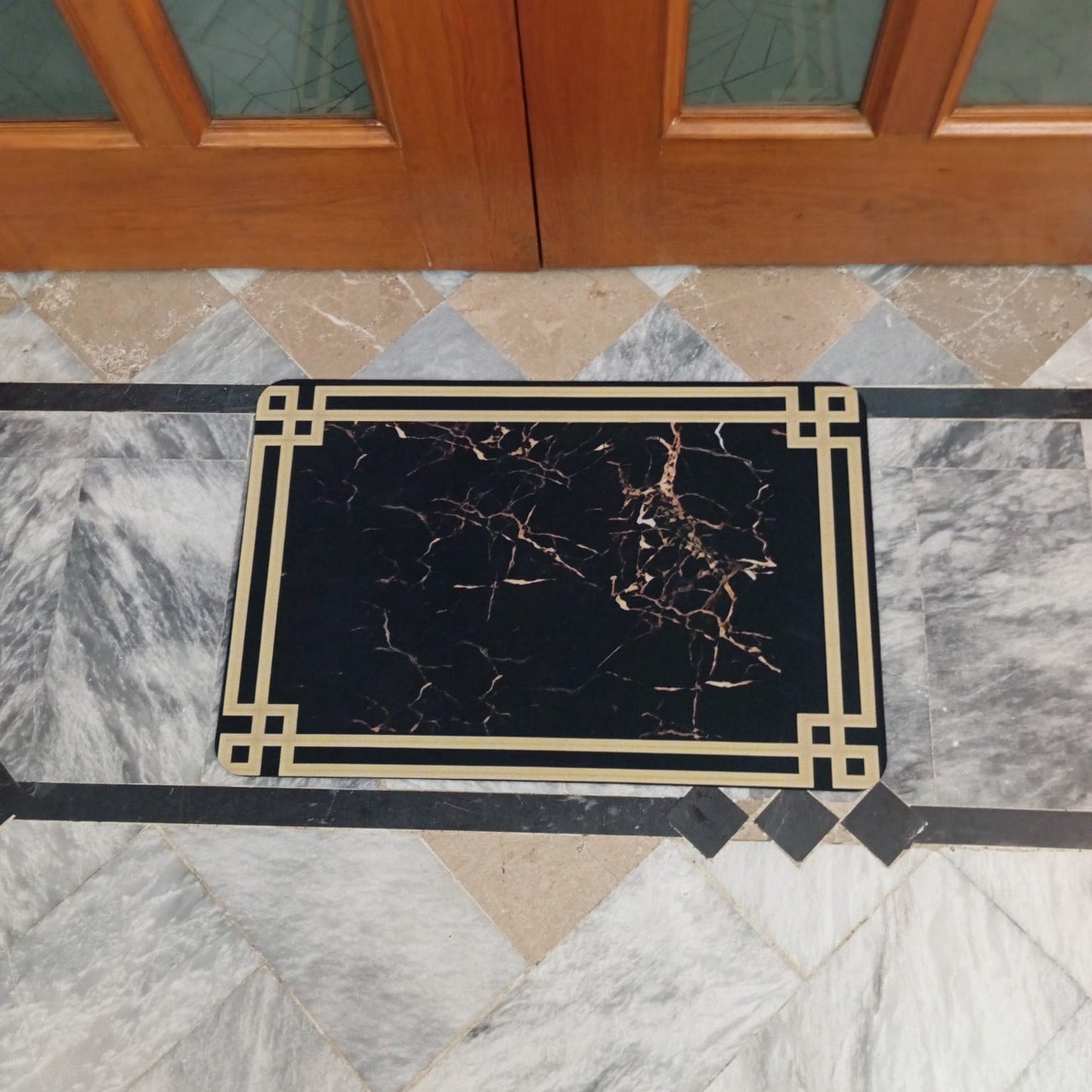 Decorative doormat with marble pattern on a marble floor in front of a wooden door.