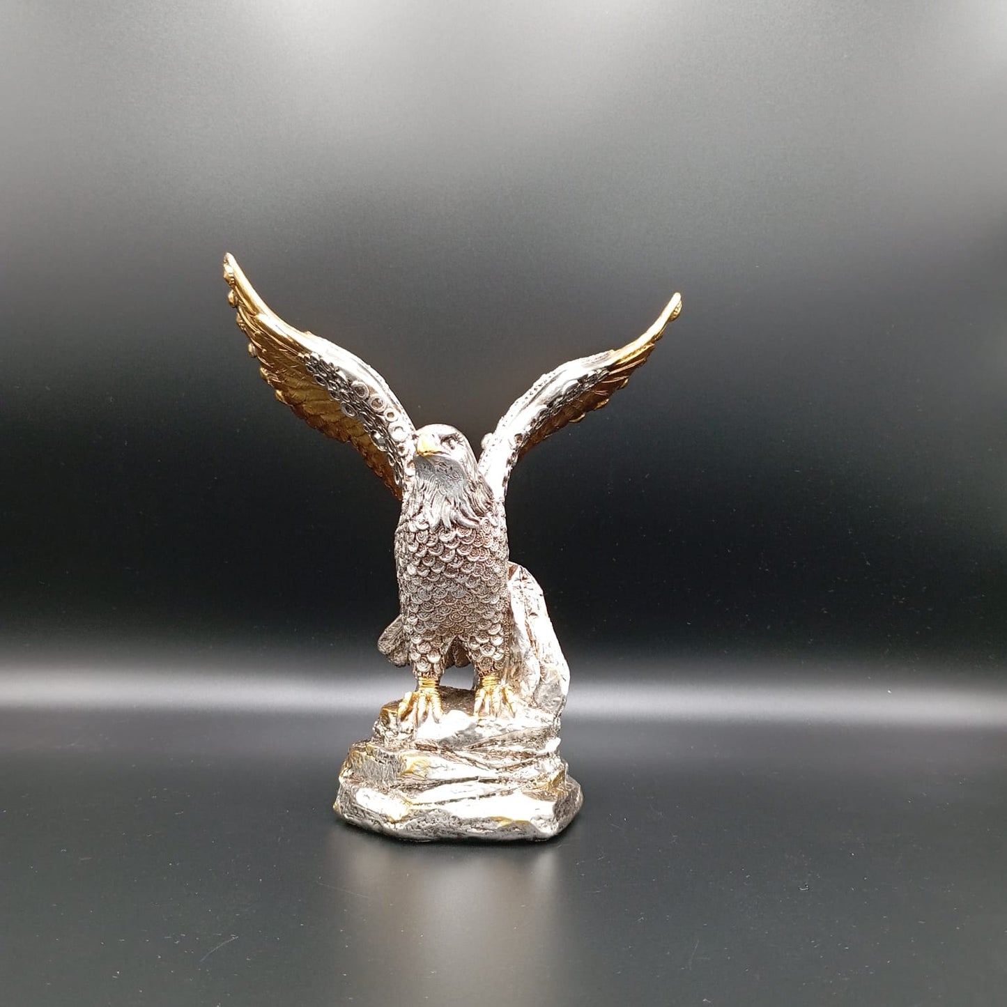Silver eagle figurine with gold wings on a dark background