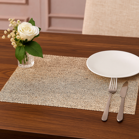 Table setting with a white plate, fork, knife, and vase of flowers on a wooden table.