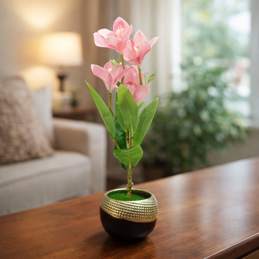 Decorative pink flower arrangement in a gold-rimmed pot on a wooden table.