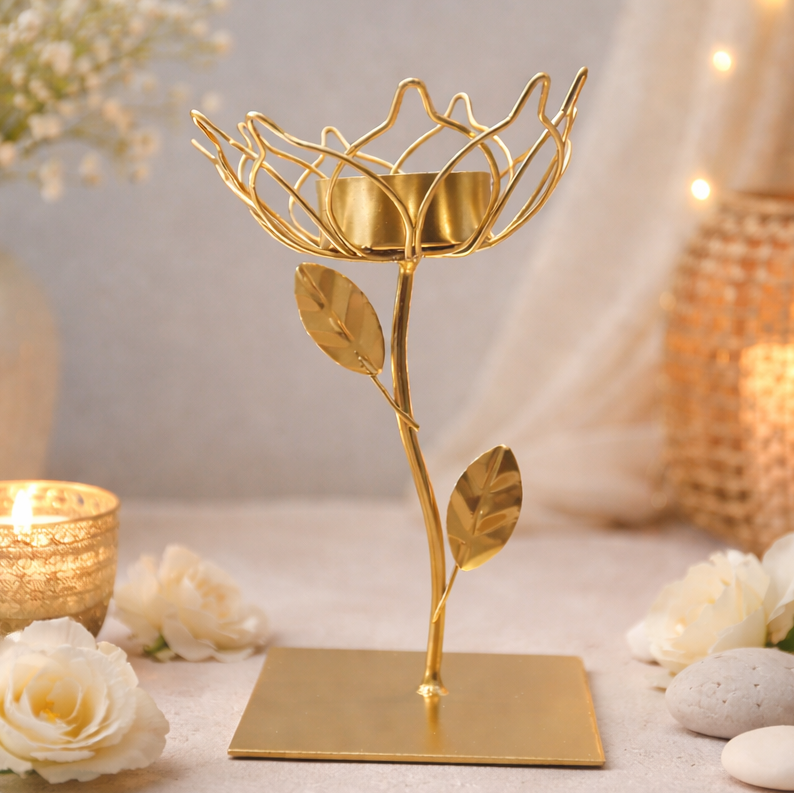 Gold decorative candle holder shaped like a leaf on a soft background with flowers and candles.