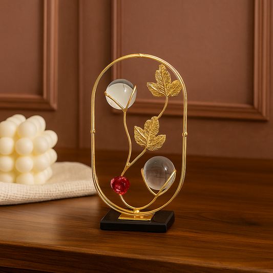 Decorative lamp with gold frame, red berry, and white sphere on a wooden surface.