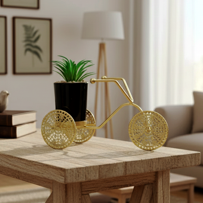 Decorative gold bike planter with a plant on a wooden table in a living room.