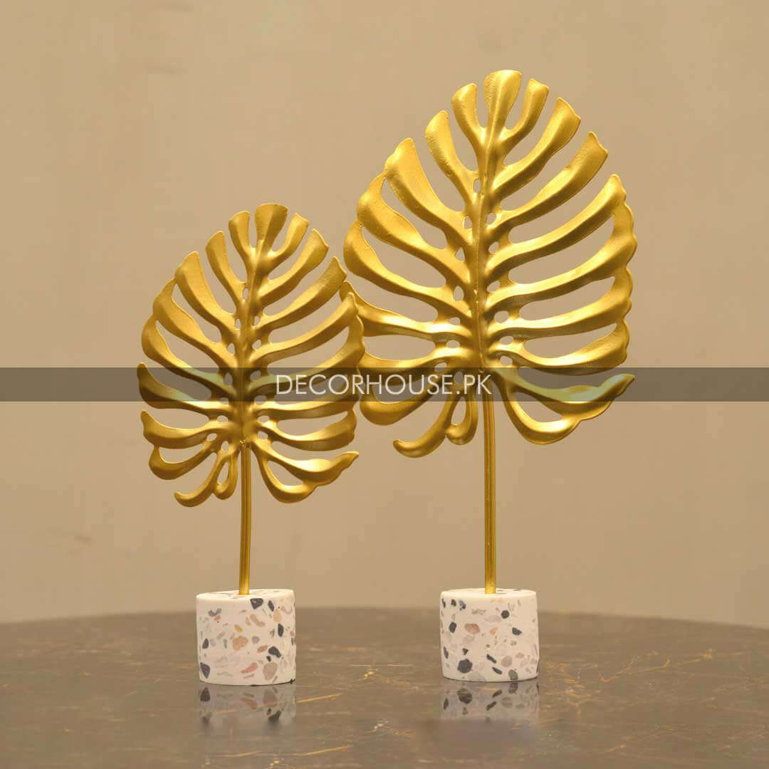 Elegant gold leaf decor featuring two intricately designed leaf ornaments on a terrazzo base for stylish home decoration.
