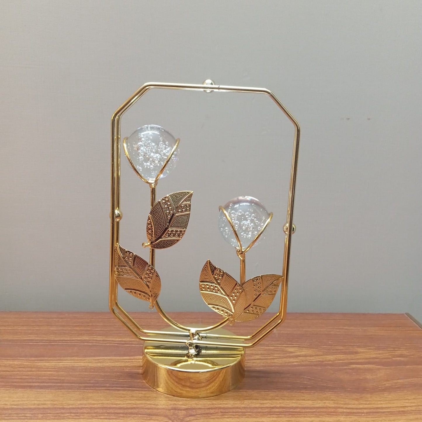 Decorative gold lamp with leaf design on a wooden surface