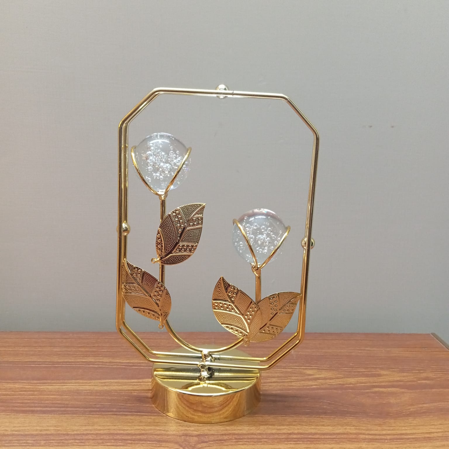 Decorative gold lamp with leaf design on a wooden surface