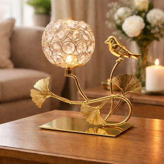 Decorative table lamp with crystal design and bird on a branch, placed on a wooden surface.