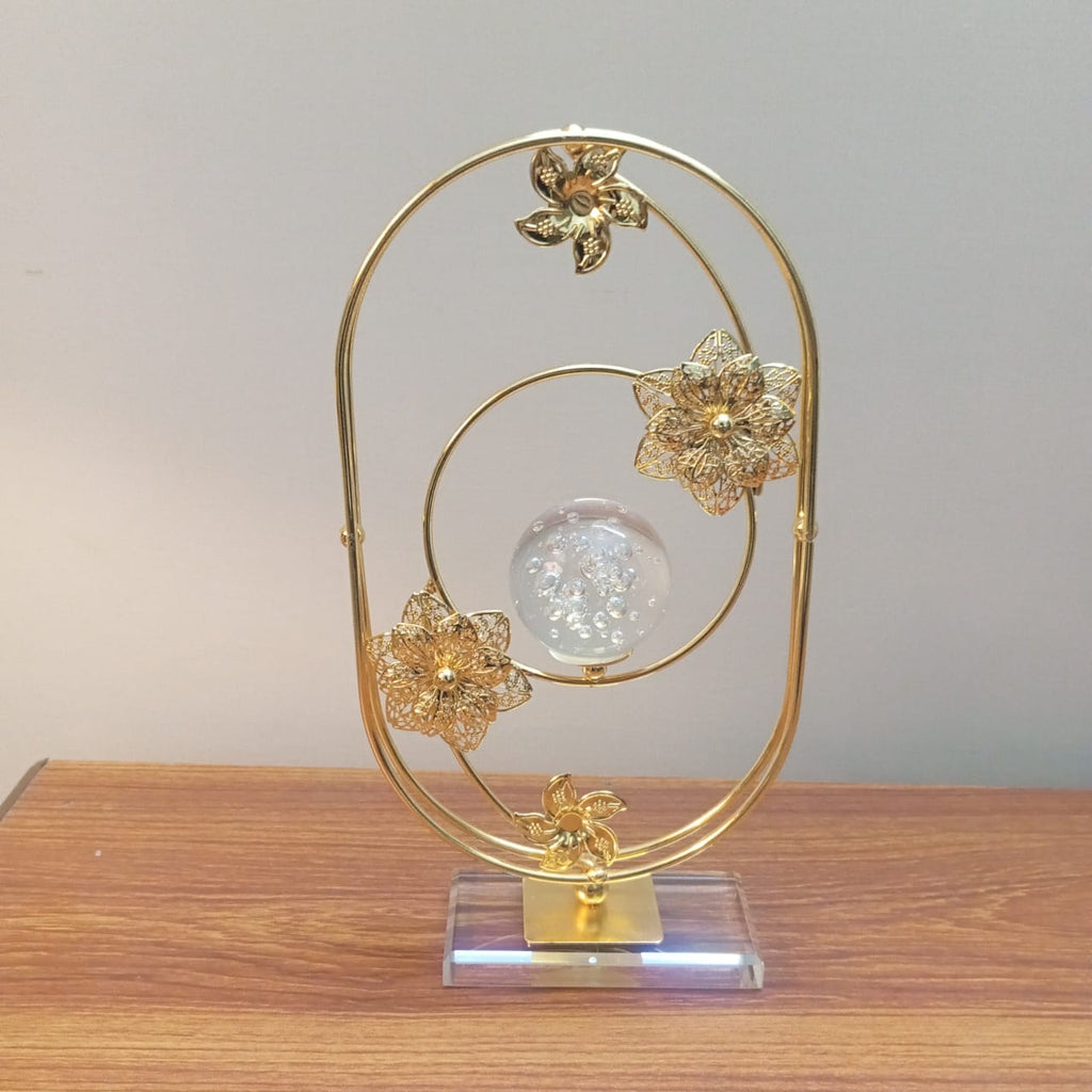 Decorative gold metal sculpture with floral designs on a wooden surface