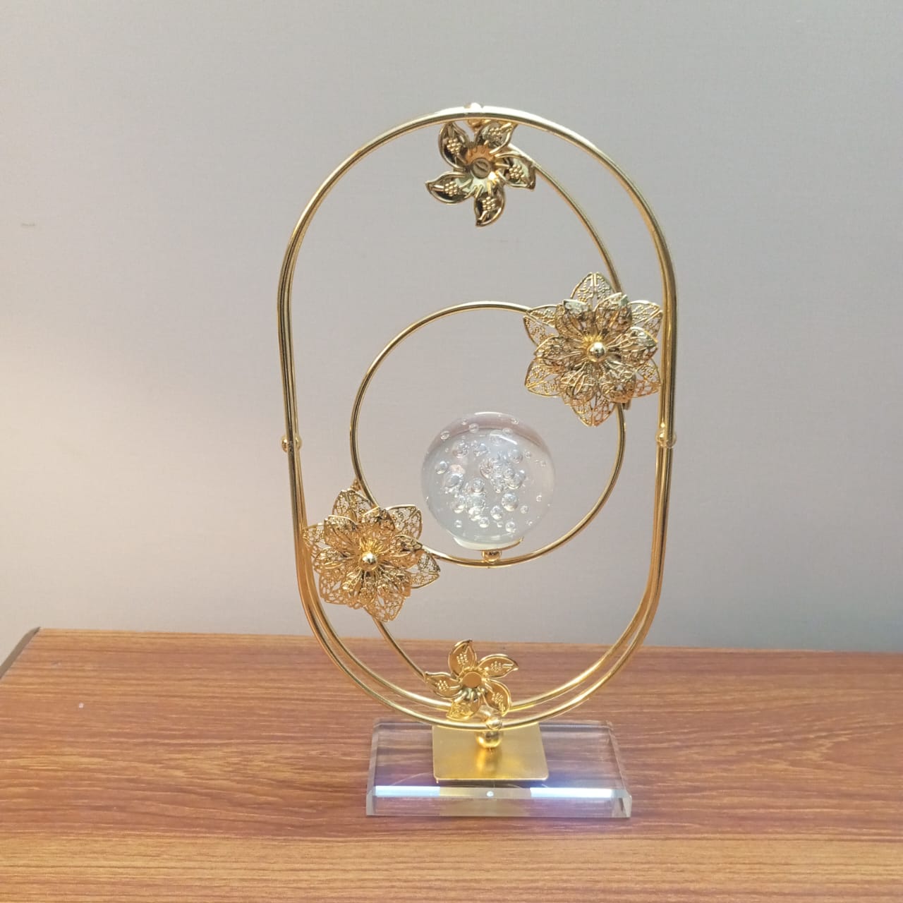 Decorative gold metal sculpture with floral designs on a wooden surface