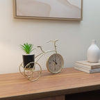 Decorative clock shaped like a bicycle with a plant on a wooden surface