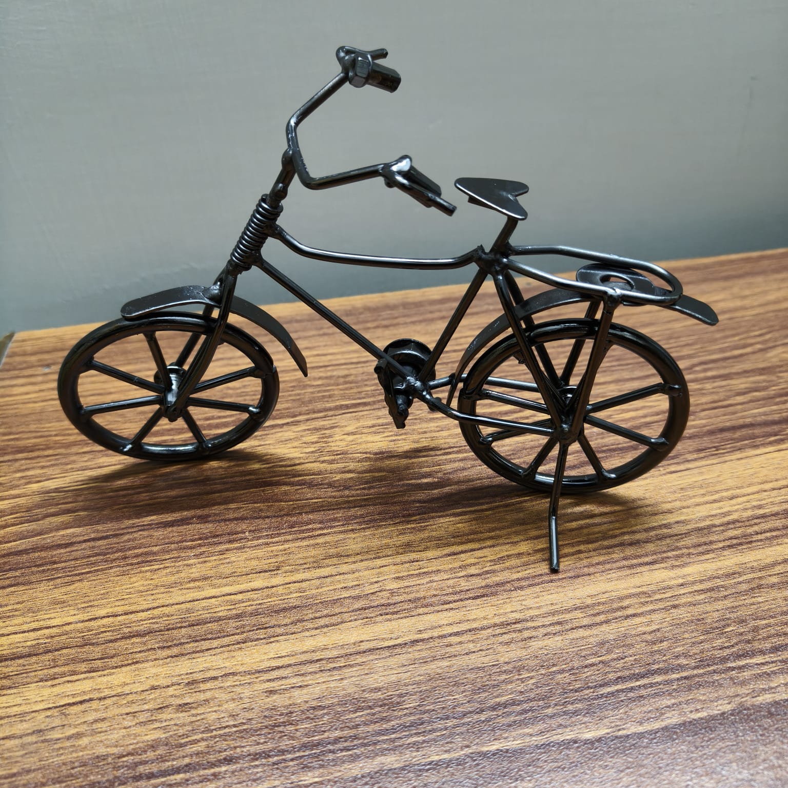 Black bicycle model on a cobblestone street with a vintage lamp and car in the background