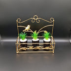 Decorative gold metal stand with three small potted plants on a black background