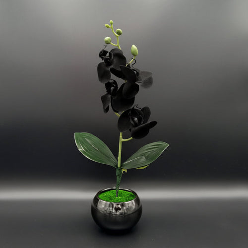 Pink artificial orchid plant in a black pot on a dark background