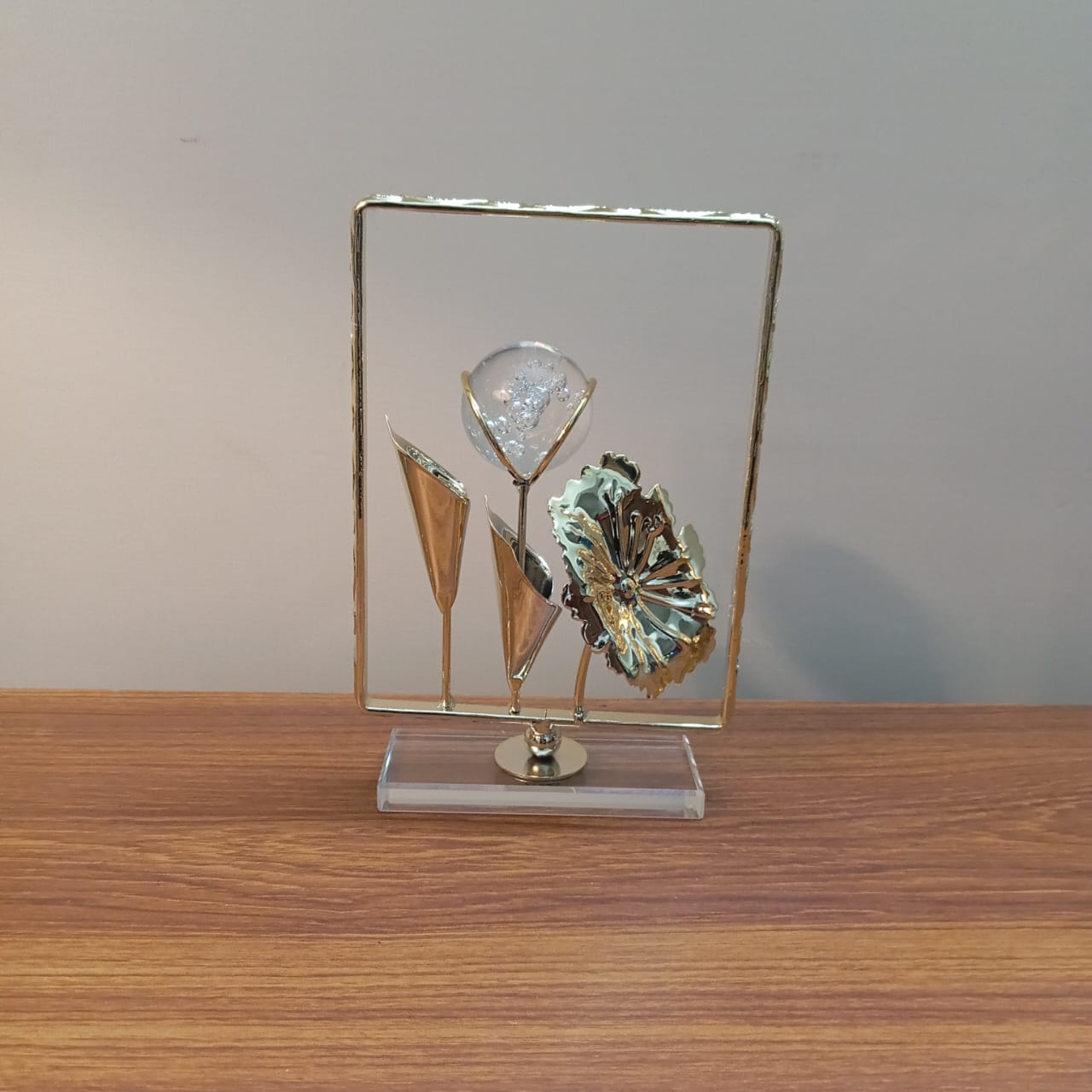 Decorative sculpture on a stand with a glass panel on a wooden surface