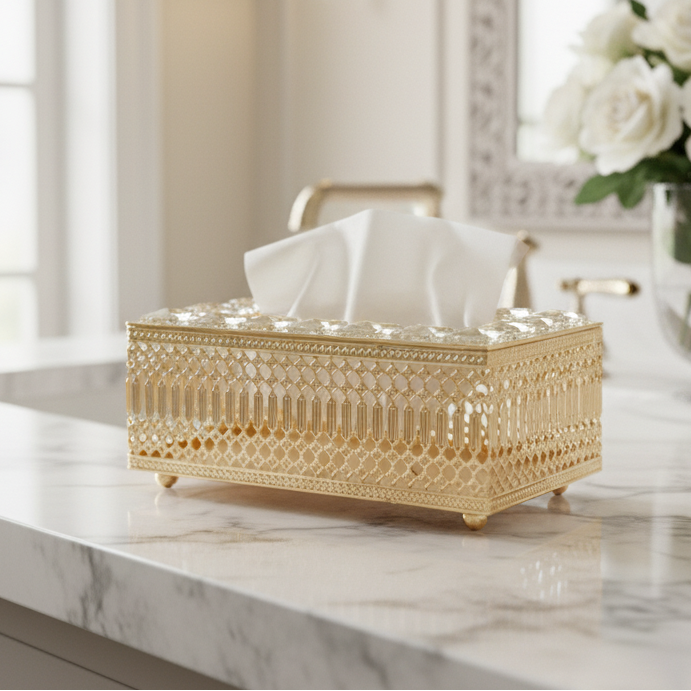 Decorative gold tissue box on a marble countertop with a vase of white flowers in the background.